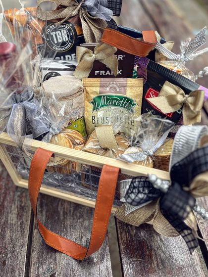 A close-up view of the curated items inside a CEO's gift basket. You can see the variety of textures and products, from crunchy bruschetta to fine chocolates, all elegantly tied with custom ribbons.