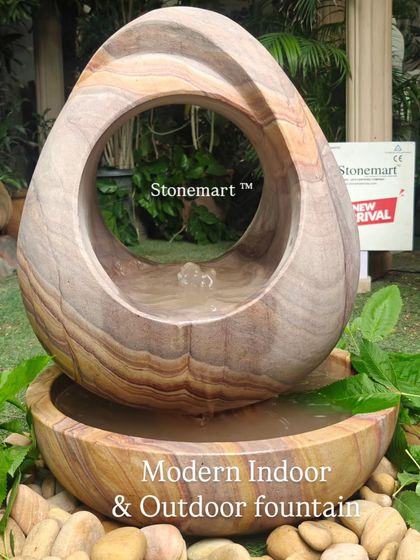 This view of the abstract Rainbow Sandstone fountain emphasizes its suitability for both indoor and outdoor settings, surrounded by natural elements.