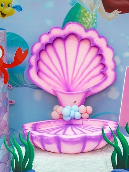 A close-up of the mermaid-themed photo booth decor, featuring a large pink clamshell and friendly sea creatures.