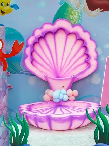 A close-up of the mermaid-themed photo booth decor, featuring a large pink clamshell and friendly sea creatures.