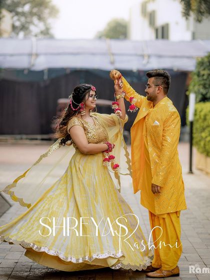 A playful and romantic portrait of the couple, "Shreyas & Rashmi," during their Haldi celebration. The groom twirls his bride, showing off her beautiful yellow lehenga and their happy connection.