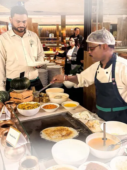 A chef preparing fresh dosas at a live counter. While our roots are Punjabi, we also excel at other regional Indian cuisines to provide a diverse menu.