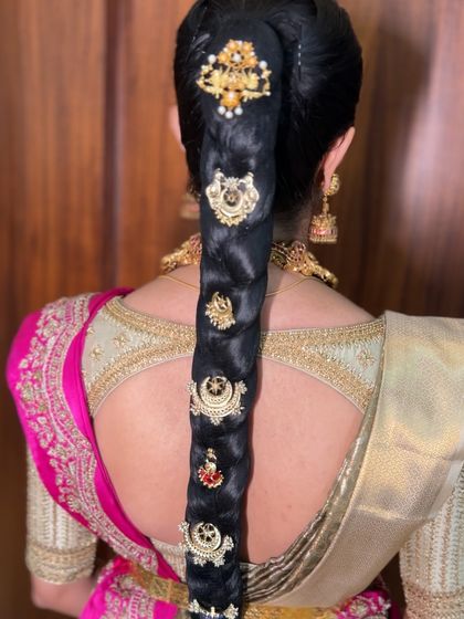 A detailed view of a high ponytail braid, elegantly decorated with multiple pieces of traditional temple jewellery along its length. This is a modern take on the classic bridal braid.