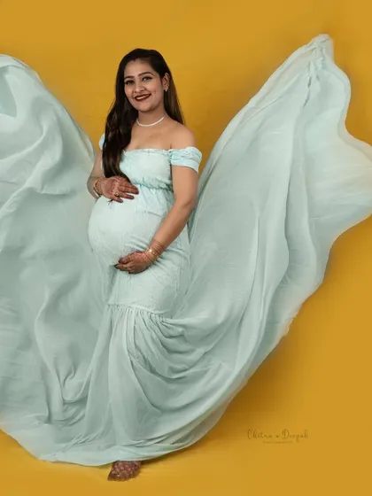The beauty of a fabric toss. The mint green gown flows like wings against the bright yellow background, creating a dynamic and joyful image.