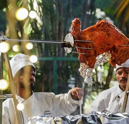 Our chefs expertly managing the live rotisserie for our famous Royal Raan, a highlight of our wedding catering packages.