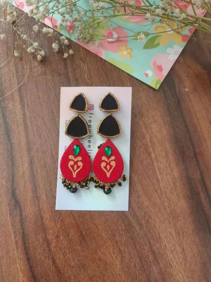 These two-part hand-painted earrings feature a black triangular stud and a red teardrop piece with a heart motif. The small black bead details add a delicate finishing touch.