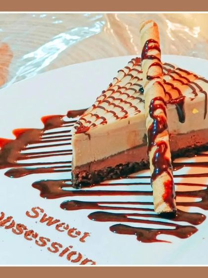Another look at our beautifully plated chocolate cheesecake slice, served with a decorative wafer roll. It's a perfect example of the artistry I bring to my desserts.