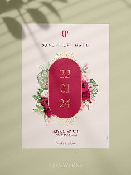 A bold and modern Save the Date design. The deep magenta oval with gold foil accents creates a striking focal point, framed by watercolor florals for a contemporary yet romantic feel.