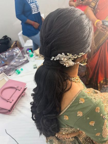A view of the elegant textured ponytail I created for Anitha's reception. The hairstyle is adorned with a delicate accessory, adding a touch of sophistication.