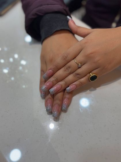 This set of coffin nail extensions with a glittery French tip is perfect for making a statement. The silver sparkle is both elegant and fun.