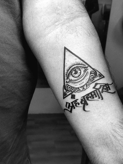 The sacred Sanskrit phrase "Aham Brahmasmi" paired with an all-seeing eye within a triangle. This inner forearm tattoo combines spiritual text with powerful symbolism.