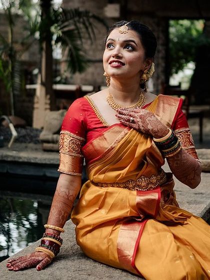 A bride sits by a small pond, her expression full of wonder and joy.