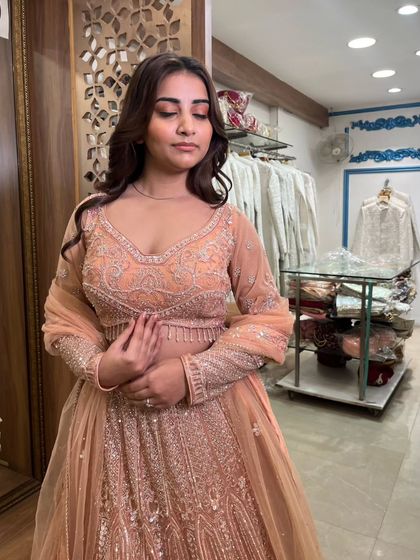 A close-up shot capturing the delicate embroidery on the blouse and the soft peach color.