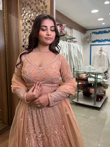 A close-up shot capturing the delicate embroidery on the blouse and the soft peach color.