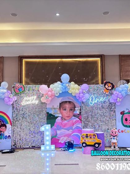 A large-scale Cocomelon theme for Sayansh's first birthday. This setup includes multiple backdrops, character cutouts, neon signs, and a central photo display, perfect for a big celebration.