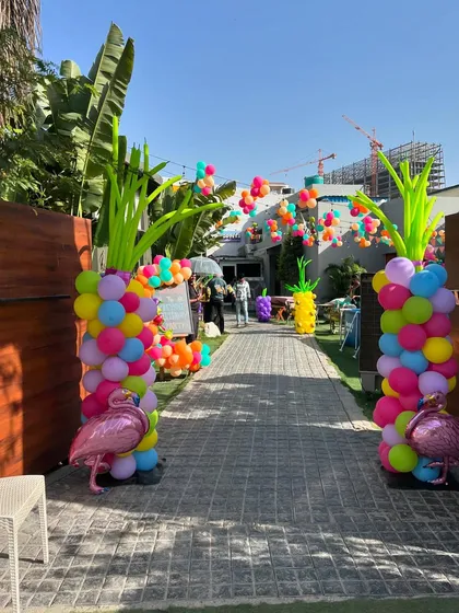 A still shot of the vibrant tropical party entrance with pineapple and flamingo decorations.
