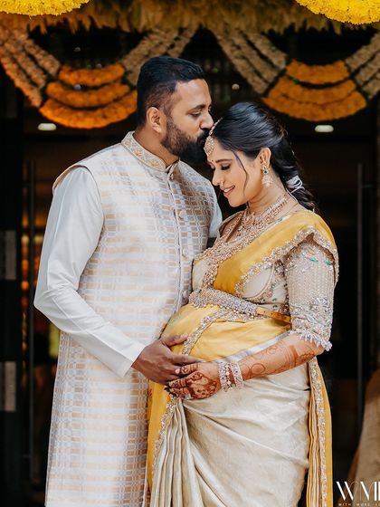 A tender moment between my husband and me at my baby shower. Our coordinated cream and yellow outfits were designed to celebrate our growing family.
