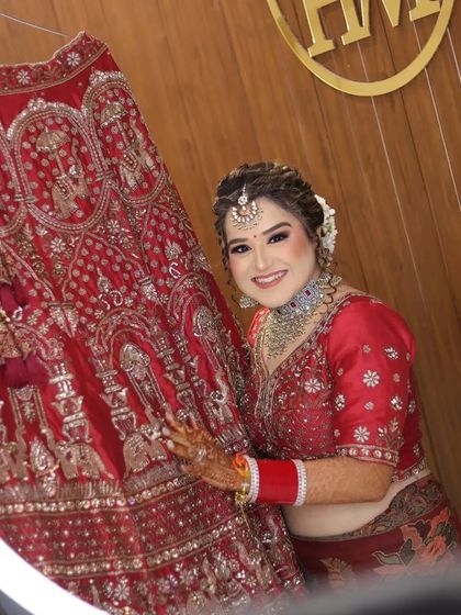 A happy and radiant portrait of the bride, framed by a ring light. She is proudly showcasing her wedding lehenga, and her smile says it all.
