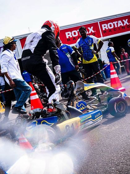 A driver jumps into his kart in the pit lane, ready to head out.