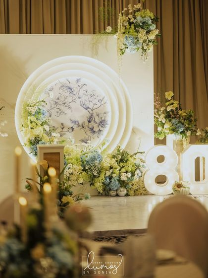 A personalized 80th birthday stage featuring indigo prints and marquee lights. The decor is a beautiful tribute, reflecting the celebrated individual's life and personality.