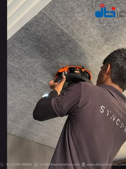 Our installation process is meticulous. This shot captures our technician, wearing a shirt with our SyncPro brand, fitting a speaker into an acoustically treated ceiling, demonstrating our commitment to both quality components and expert installation.