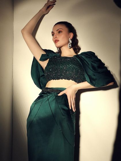 A dramatic pose in an emerald green outfit with statement puff sleeves. The use of shadow and light creates a powerful, high-fashion image.