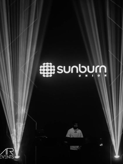 A dramatic black and white shot of me on the Sunburn stage, framed by two powerful spotlights.