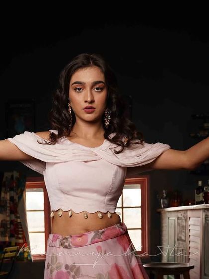 The draped chiffon on the off-shoulder crop top creates a soft and romantic neckline.