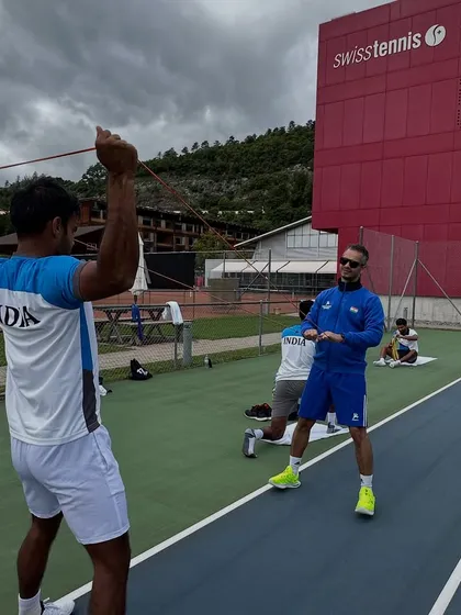 A typical day at the office during the Davis Cup in Switzerland. Here, I'm guiding an athlete through resistance band exercises for shoulder activation and stability, a crucial pre-practice routine for tennis players.