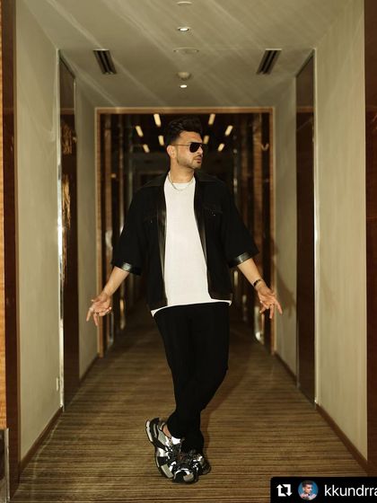 A full-length view of the modern, casual-luxe look for Karan Kundrra. The oversized jacket paired with sleek trousers and statement sneakers creates a confident, fashion-forward style.