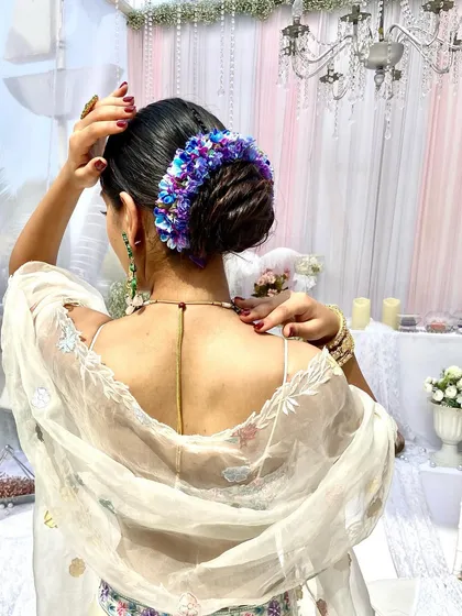 A stunning bridal bun adorned with a full wrap of vibrant blue and purple hydrangeas. This creates a dramatic and unforgettable look.