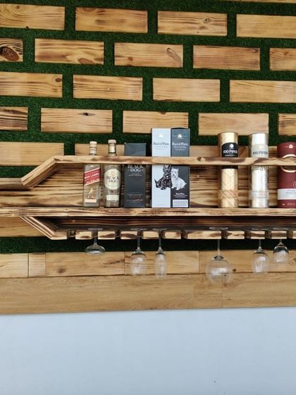 This close-up shows the detail of the bottle-shaped shelf, fully stocked. It demonstrates the unit's practical use for storing various bottles and glassware, blending art with utility.