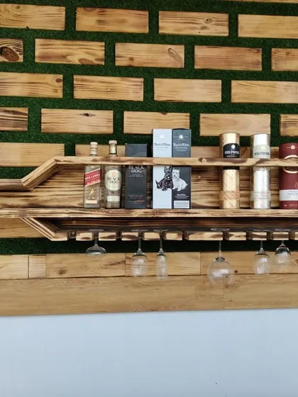 This close-up shows the detail of the bottle-shaped shelf, fully stocked. It demonstrates the unit's practical use for storing various bottles and glassware, blending art with utility.