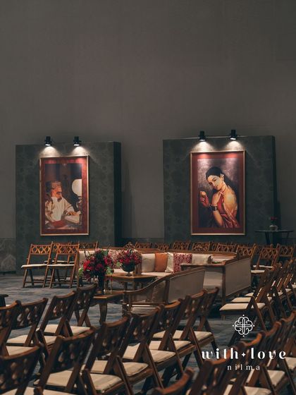 The seating area for the sangeet, where guests are surrounded by the art of Raja Ravi Varma. The design prioritizes intimate corners for conversation, with classic furniture and moody lighting.