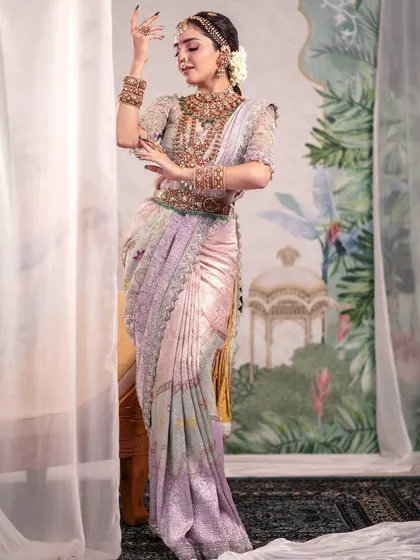 A graceful pose showing the flow and drape of a traditional pastel saree. The sheer curtains and painted background add layers of texture and depth to the shot.