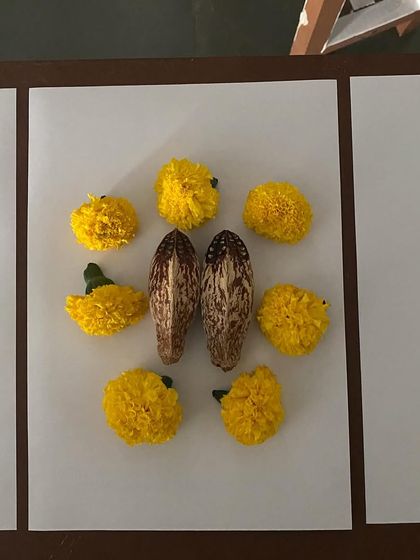 A symmetrical arrangement of marigolds and seed pods, made by a visitor.