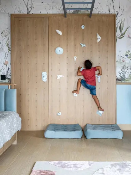 Designing for children is about sparking joy and curiosity. This bedroom features a custom rock-climbing wall that doubles as a playful art installation, encouraging adventure and activity. We believe kids' bedroom design should be imaginative, safe, and grow with them, and this space is a testament to that philosophy.