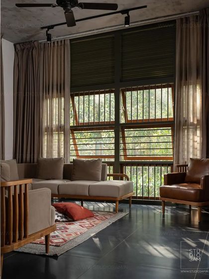The living room is a cozy space with large windows, allowing for beautiful light play and a connection to the lush exterior.