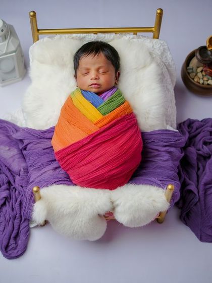 Wrapped in all the colors of the rainbow. This photo is a celebration of new life, with the baby sleeping peacefully on a miniature bed.