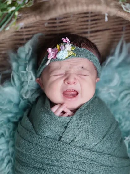 Even a little cry can make for an adorable and authentic photo. This newborn is showing off her tiny yawn or cry, a classic baby moment.