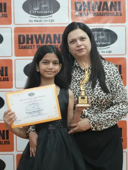 A mother and daughter duo celebrating an award at the Dhwani Kala Mahotsav.