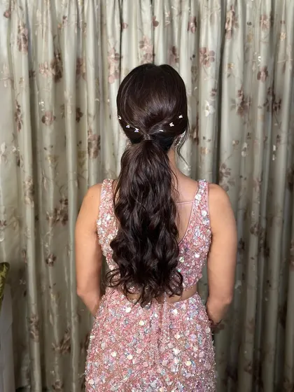 A view of the chic hairstyle, a wavy ponytail with delicate pearl accessories that add a touch of modern elegance to the Sangeet look.
