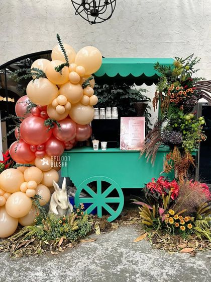 A charming drink cart decorated with a balloon garland and floral arrangements, fitting the woodland theme perfectly.