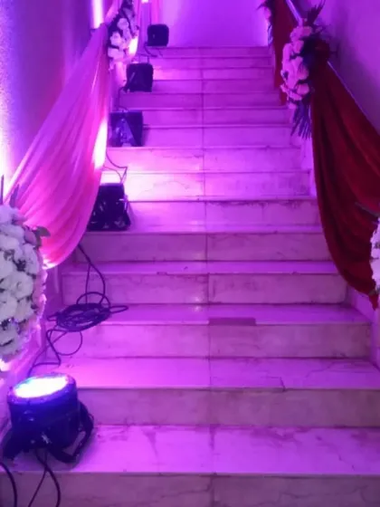 Staircase decoration for a wedding venue. We used drapes in pink and red fabric along the railings, accented with white floral bouquets and purple uplighting to make the entrance grand.