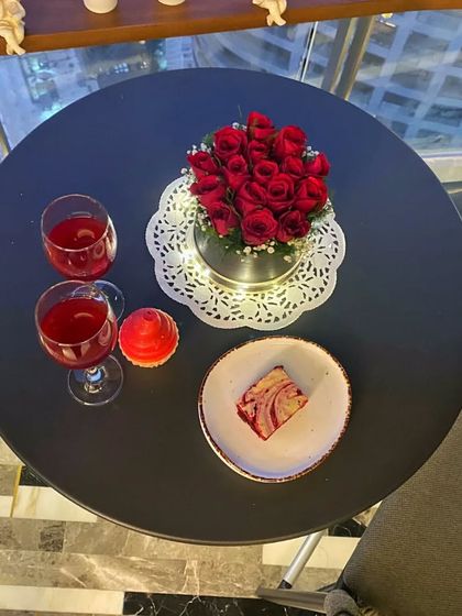 An overhead shot of the table, with red wine, a red velvet dessert, and a cupcake candle. It’s these little details that make an at-home date night feel luxurious and memorable.