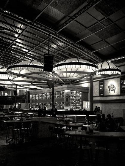 Another perspective of the bar at night, showing patrons as silhouettes against the glowing fixtures. This image captures the ambiance and energy of the space.