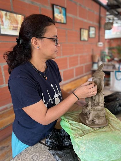 The workshop is a space for intense focus and creativity. Here, a participant is deeply engaged in sculpting her idol.