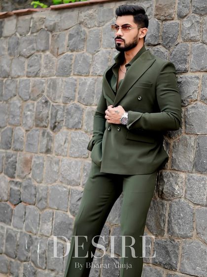 A full-length shot of the olive green suit against a stone wall. The monochromatic look is both modern and classic, exuding an air of effortless cool.