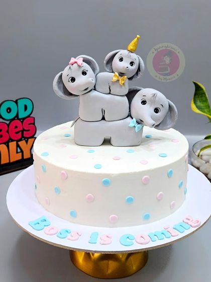 An adorable elephant-themed baby shower cake with the message "Boss is Coming". The stacked elephants are completely handmade.