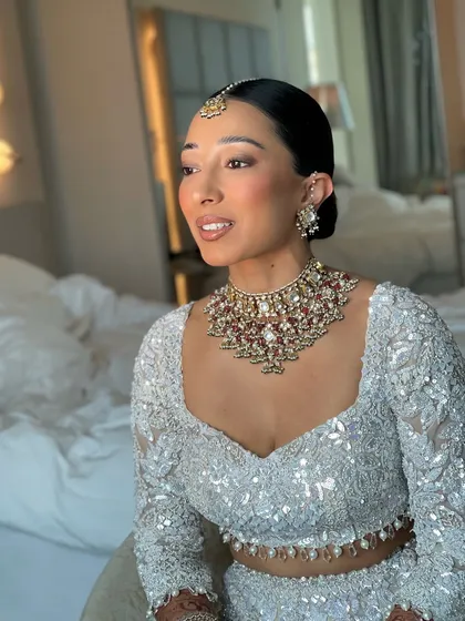 A clean, modern, and sophisticated bridal look. I created this sleek, center parted low bun to provide a perfect base for the maang tikka and to highlight the bride's features and stunning jewelry.